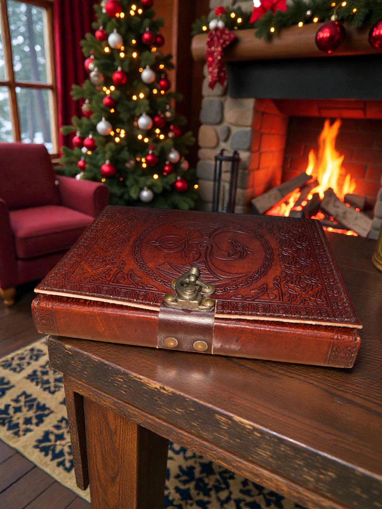 Decorative leather-bound book on a wooden table with a Christmas tree and fireplace in the background.
