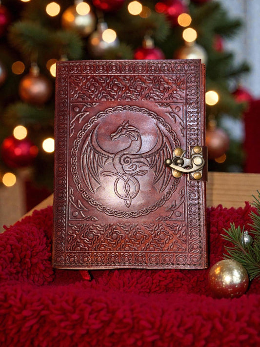 Decorative leather journal with embossed design on a red surface with Christmas tree in the background